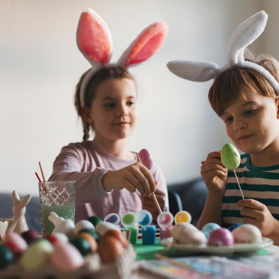 2 børn med kaninører maler påskeæg