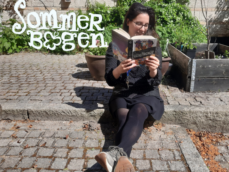 Børnebibliotekaren læser i bibliotekets gårdhave.